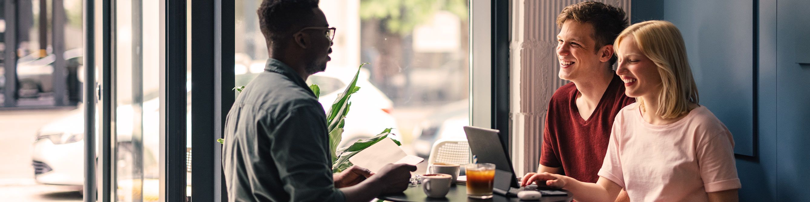Drei erwachsene Personen im Cafe und arbeiten