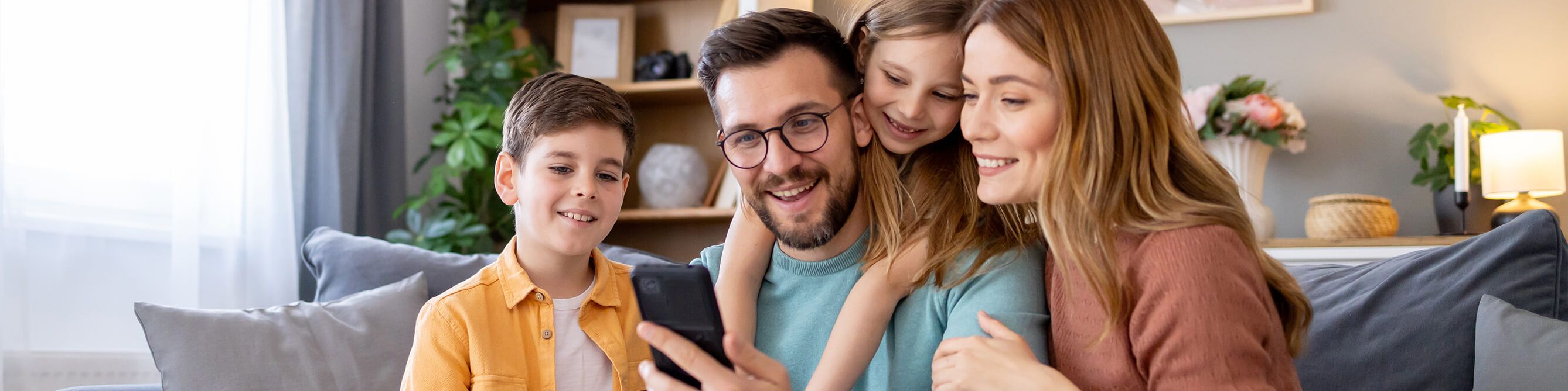 Zufriedene SV-Kunden sitzen mit der Familie auf dem Sofa