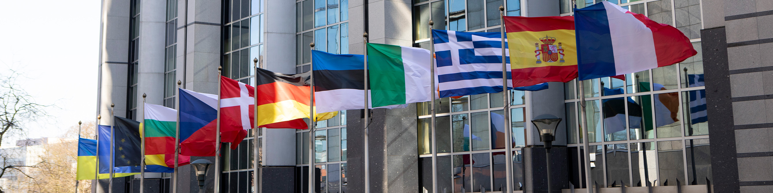 Euro Staatsanleihen - EU Flaggen wehen vor Gebäude