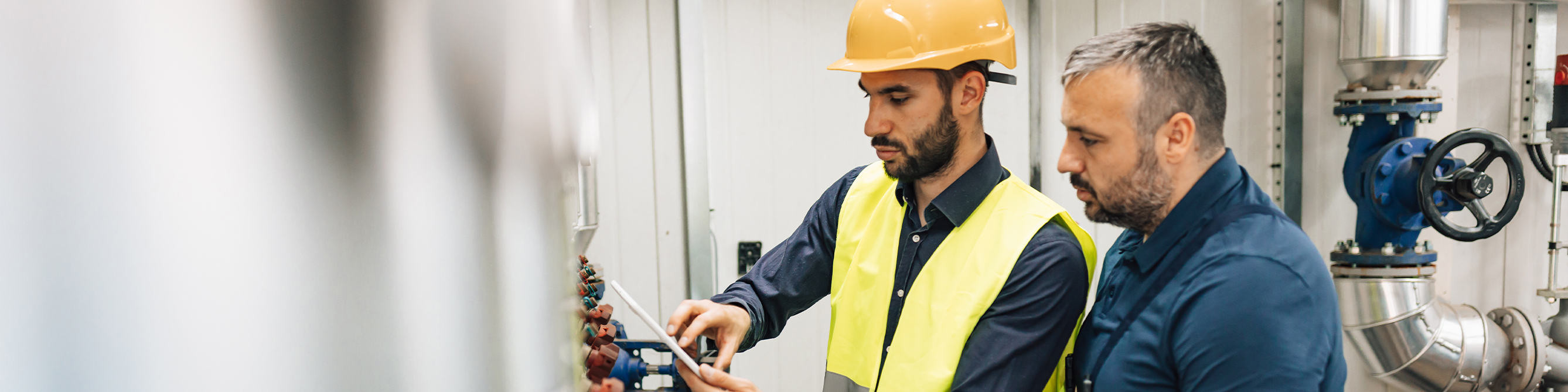 Mehrfamilienhaus -­ Männer mit Laptop vor Heizungsanlage