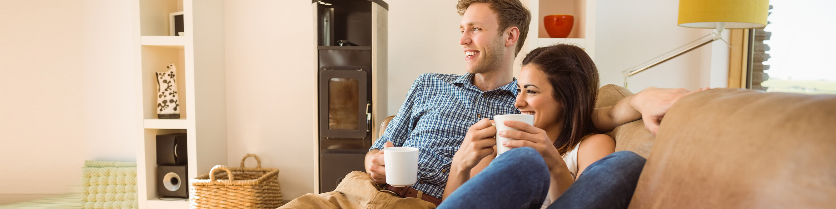 Paar liegt auf dem Sofa mit Kaffee in der Hand
