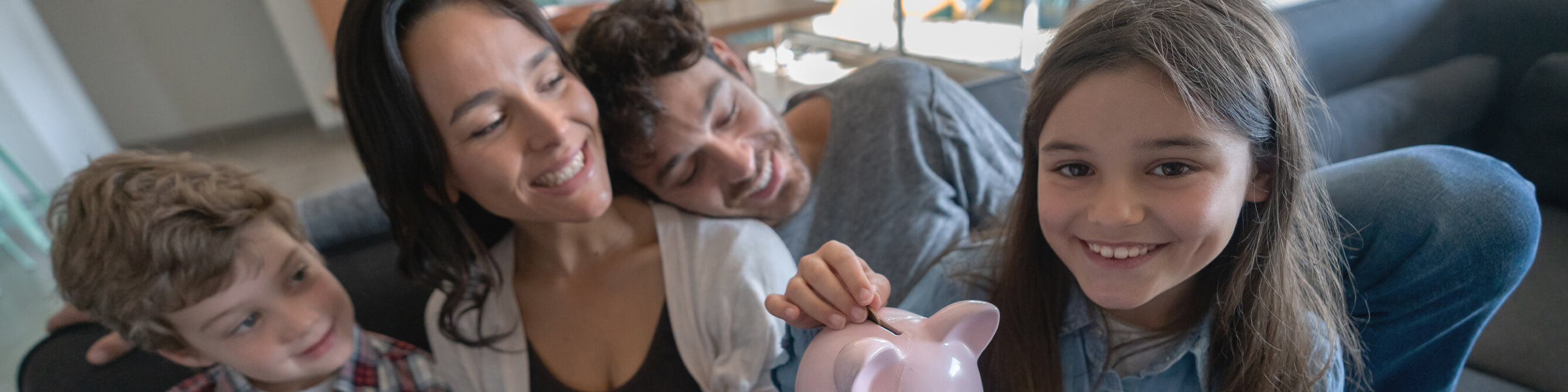 Famile mit Sparschwein auf dem Sofa