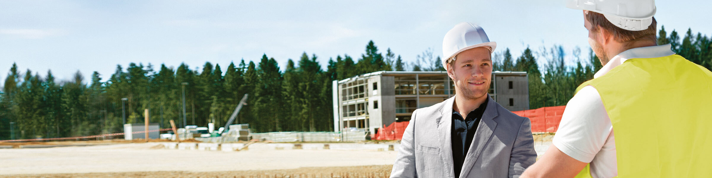 Architekt und Bauleiter stehen vor Baustelle 