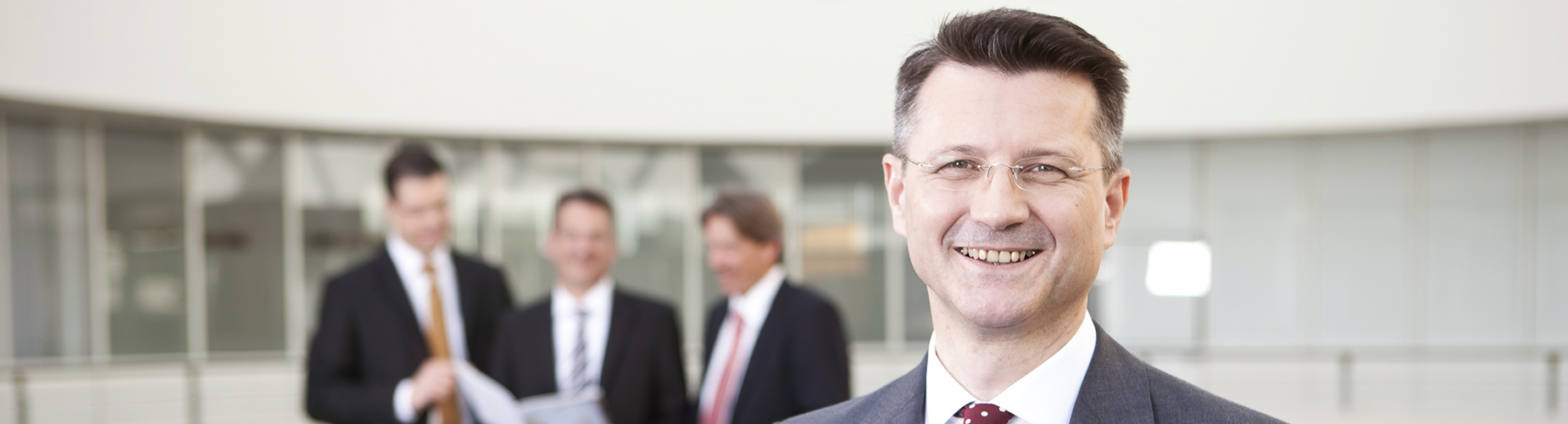 Unternehmer steht vor sich unterhaltenden Personen