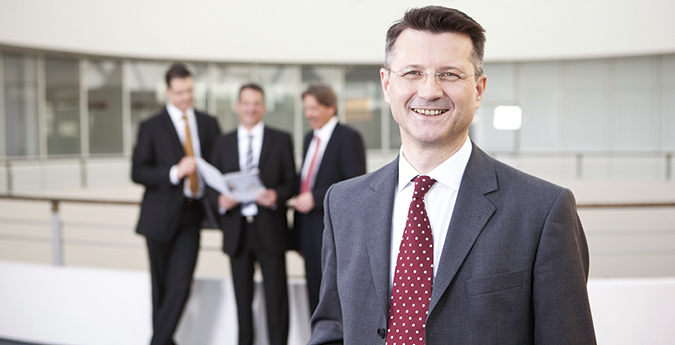 Unternehmer steht vor einer sich unterhaltenden Personengruppe