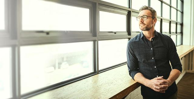 Strafrecht-Rechtsschutz-Geschaeftsmann mit Brille schaut aus dem Fenster