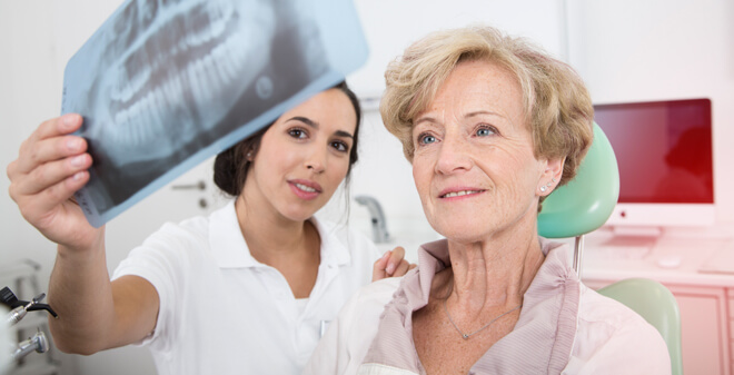 Zahnärztin mit Patientin beim Betrachten eines Röntgenbildes