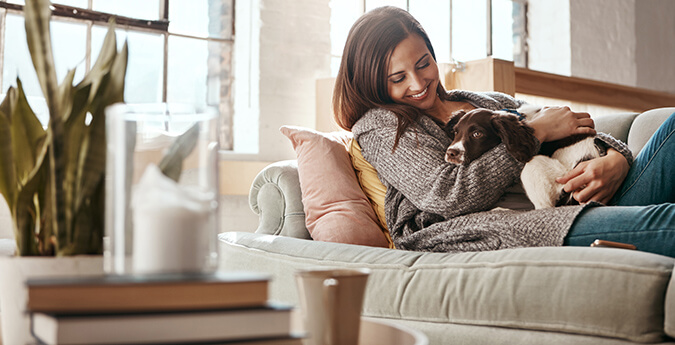 Frau liegt mit Hund auf Sofa 