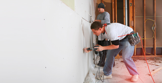 Bauhelfer-Unfallversicherung - Bauarbeiter streichen eine Wand