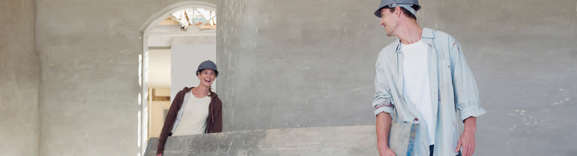 Bauherrenhaftpflicht -­ Frau und Mann tragen Balken auf Baustelle