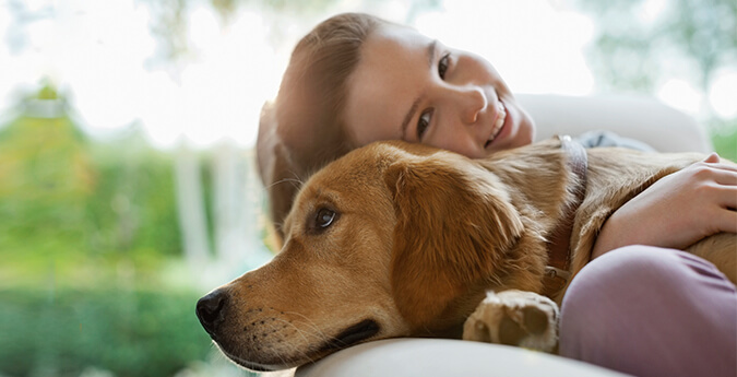 Tierhalterhaftpflicht - Frau liegt mit Hund auf dem Sofa