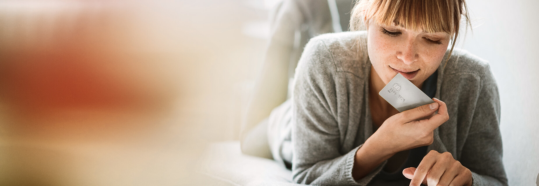 InternetSchutz - Frau liegt mit Kreditkarte und Laptop auf dem Sofa