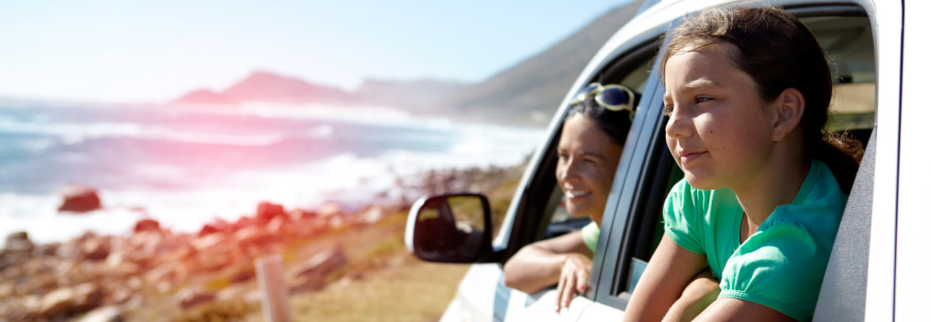 Familie schaut aus dem Autofenster auf das Meer