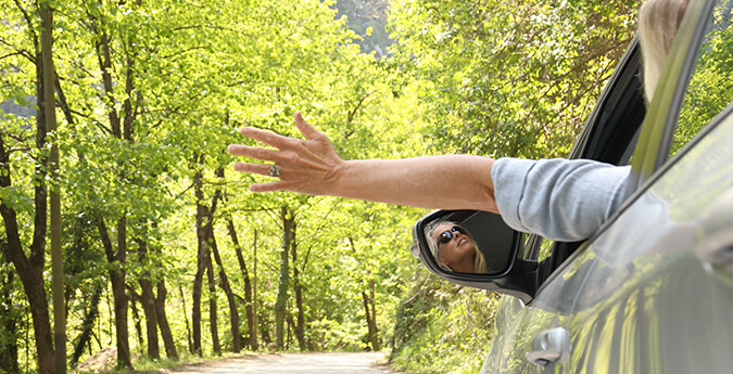 THG-Quoten - Frau fährt mit ihrem Auto durch Natur