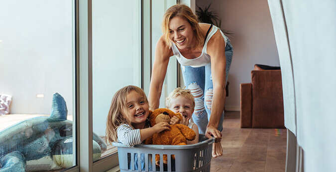 Mutter schiebt Kinder im Wäschekorb
