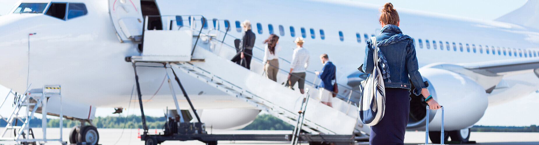 Frau geht mit Handgepäck an Bord eines Flugzeugs