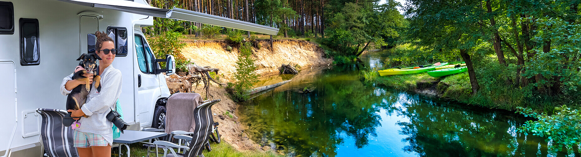Wohnmobil am Fluss und Frau mit Hund